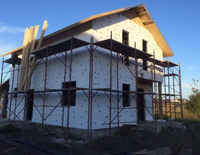 Casă în construcție cu șarpantă din lemn și schelă